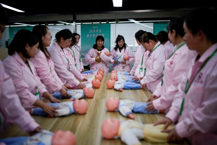 Women train with plastic baby dolls as they take part in a nursing skills class.