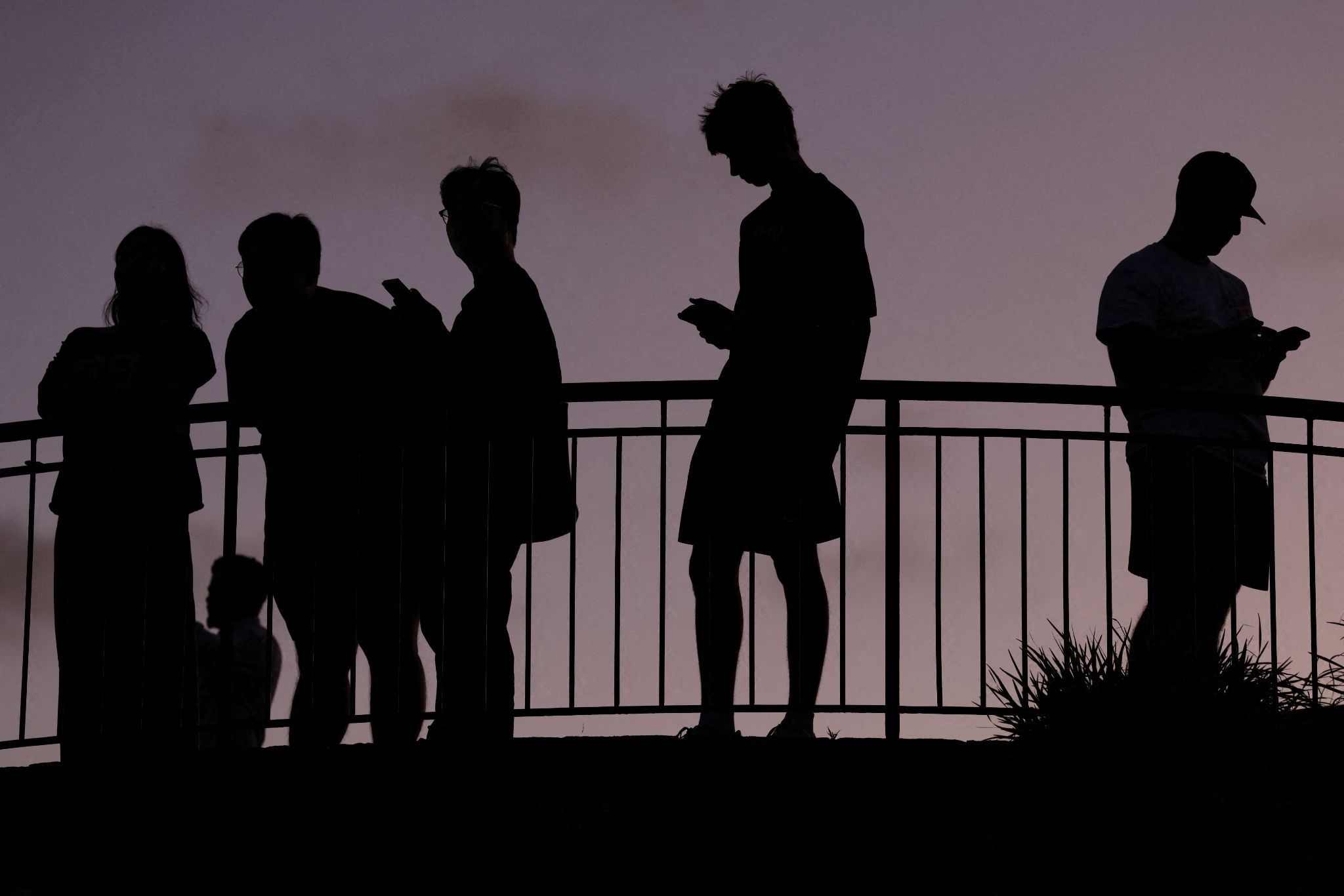 Teens use their cell phones at dusk, in Brisbane