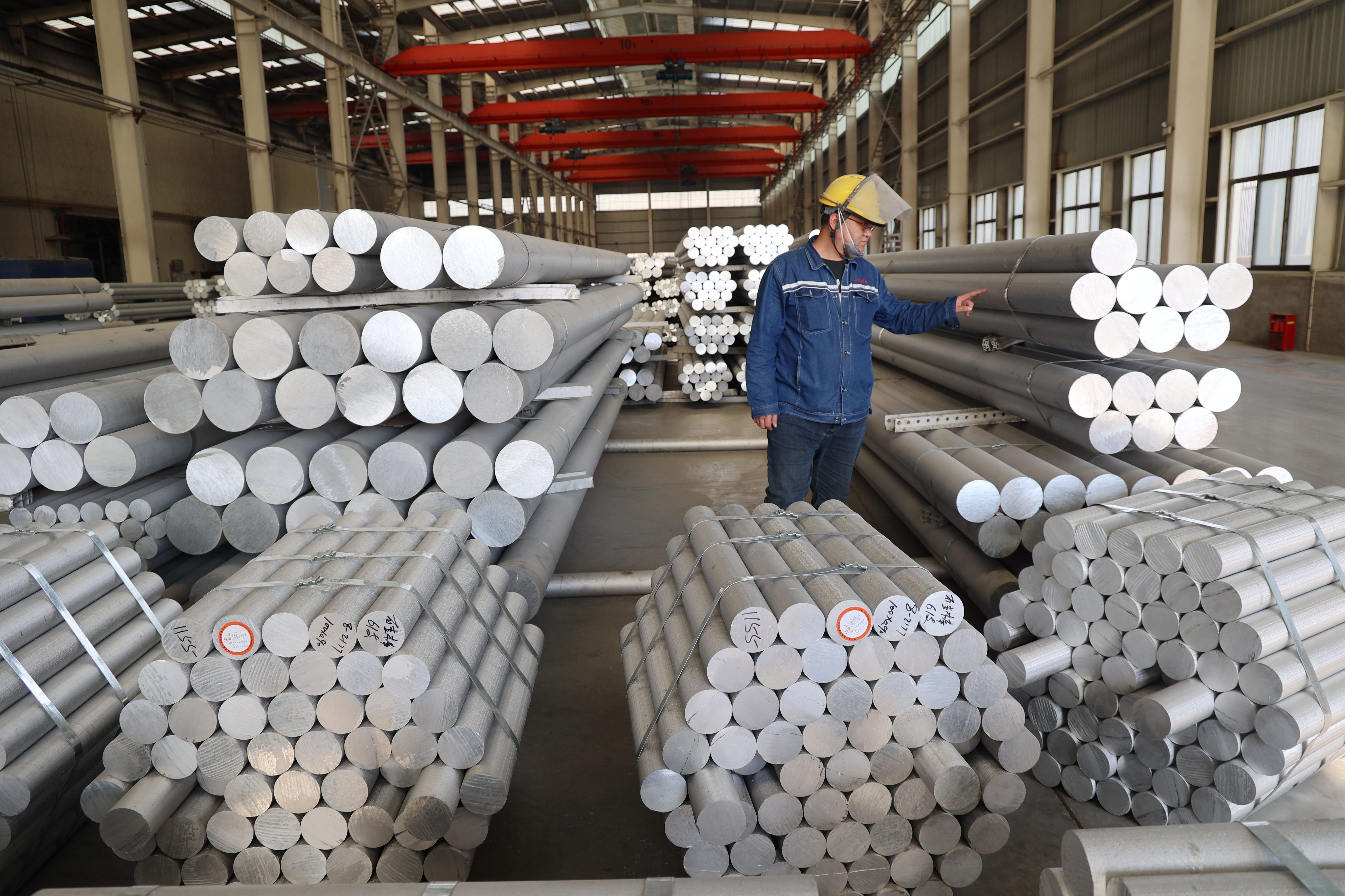 A worker checks aluminum alloy rods.