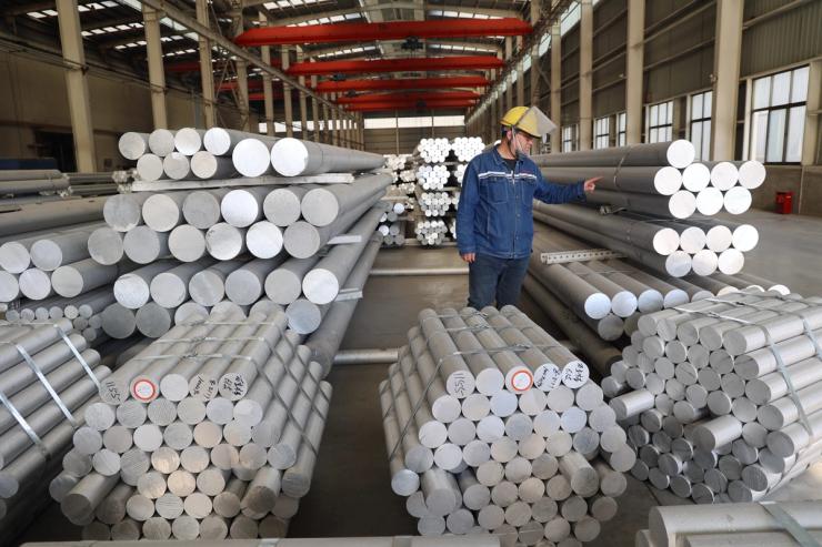 A worker checks aluminum alloy rods.