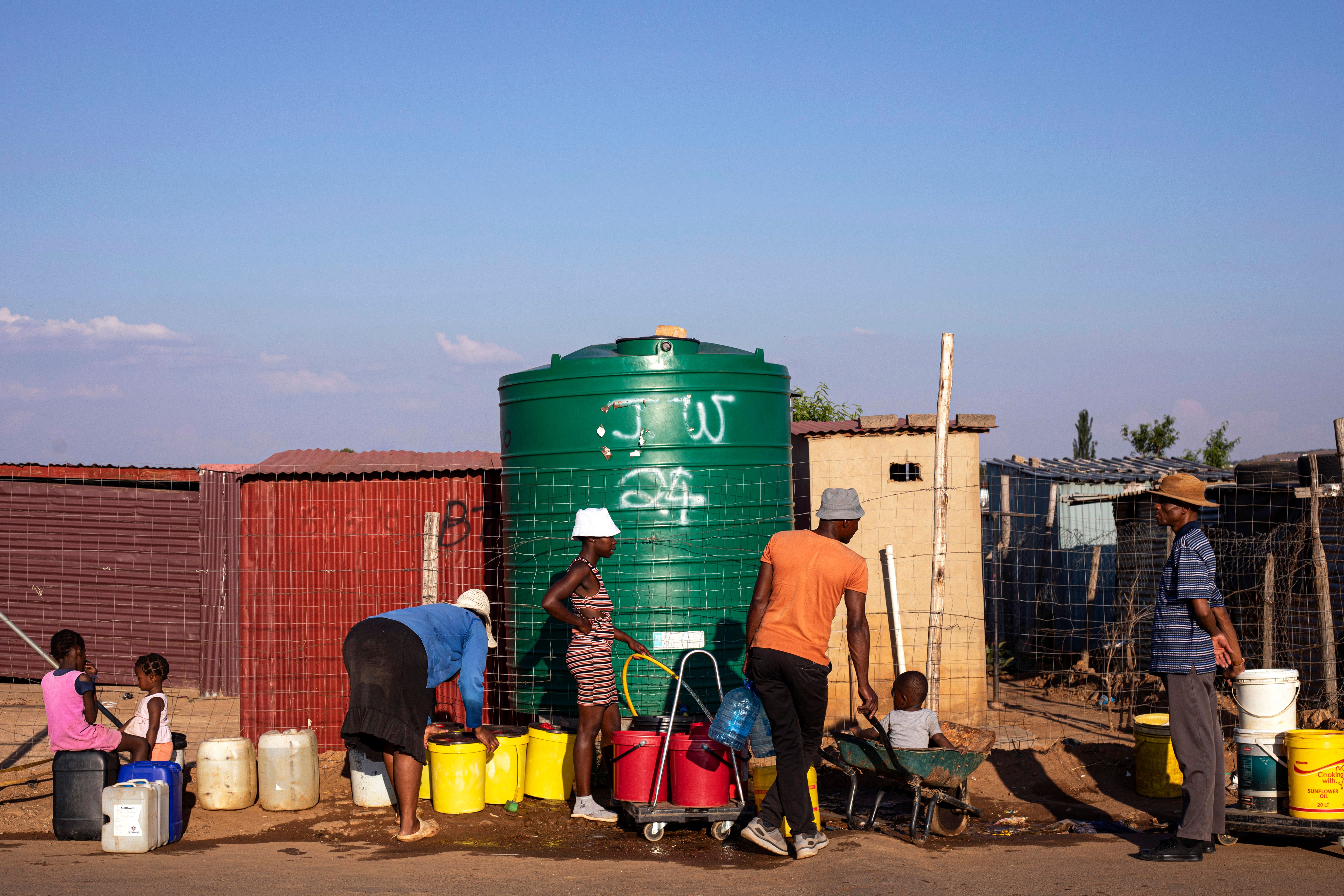 People wait in line to fetch water in a settlement.