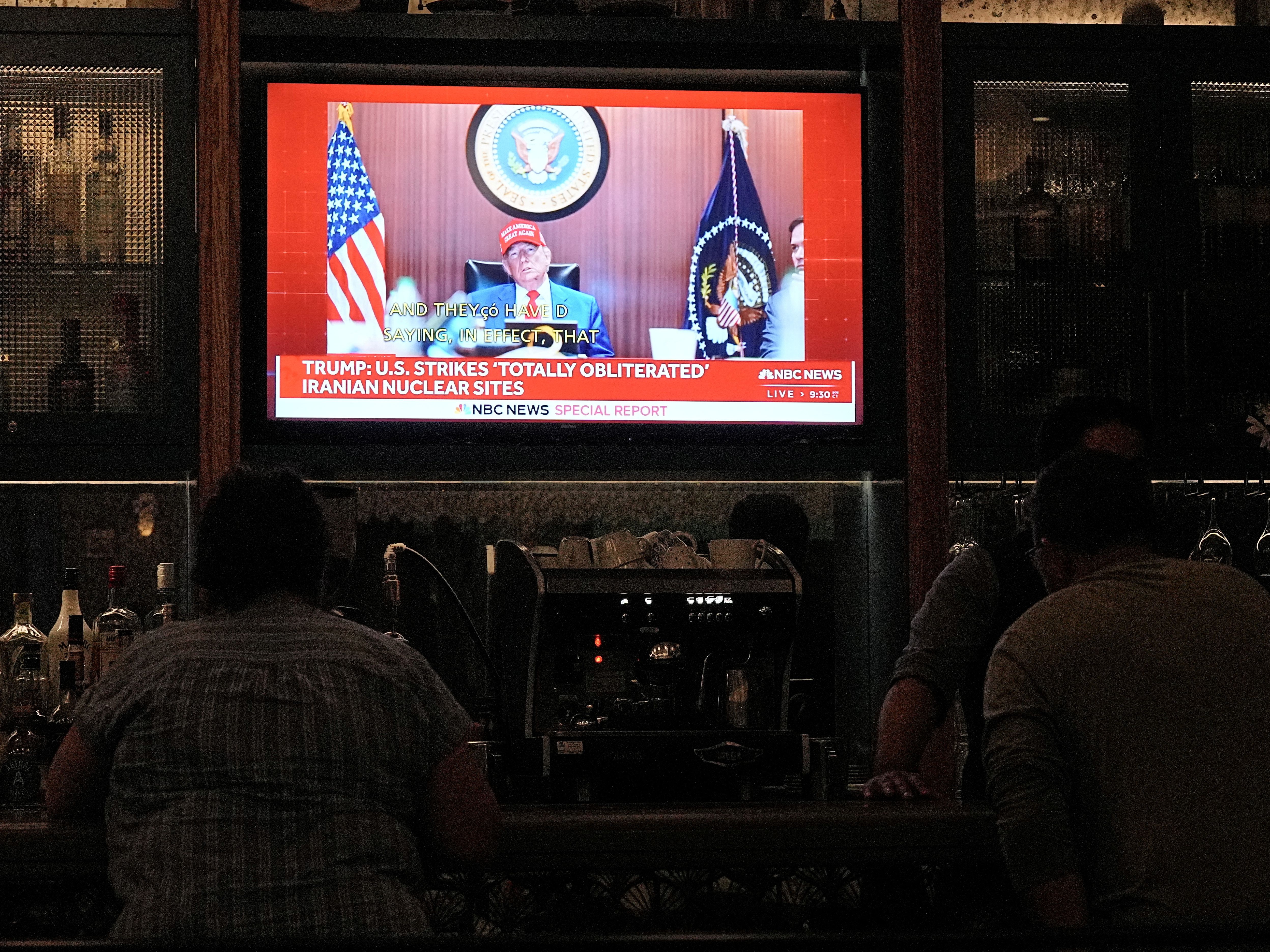 People watching news on TV at a bar