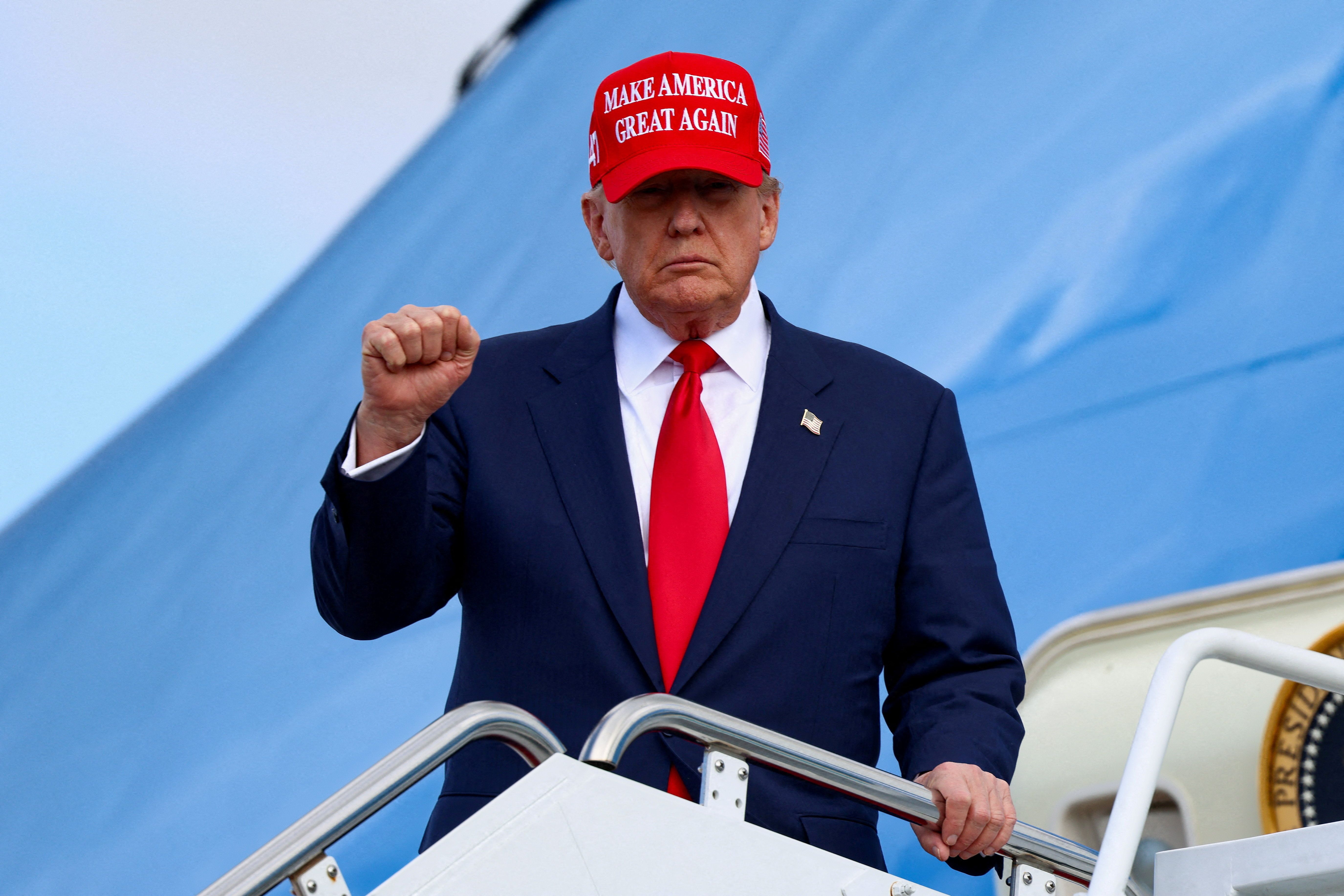 US President Donald Trump holds up a fist while standing on the staircase to Air Force One.