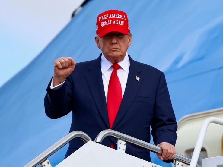 US President Donald Trump holds up a fist while standing on the staircase to Air Force One.