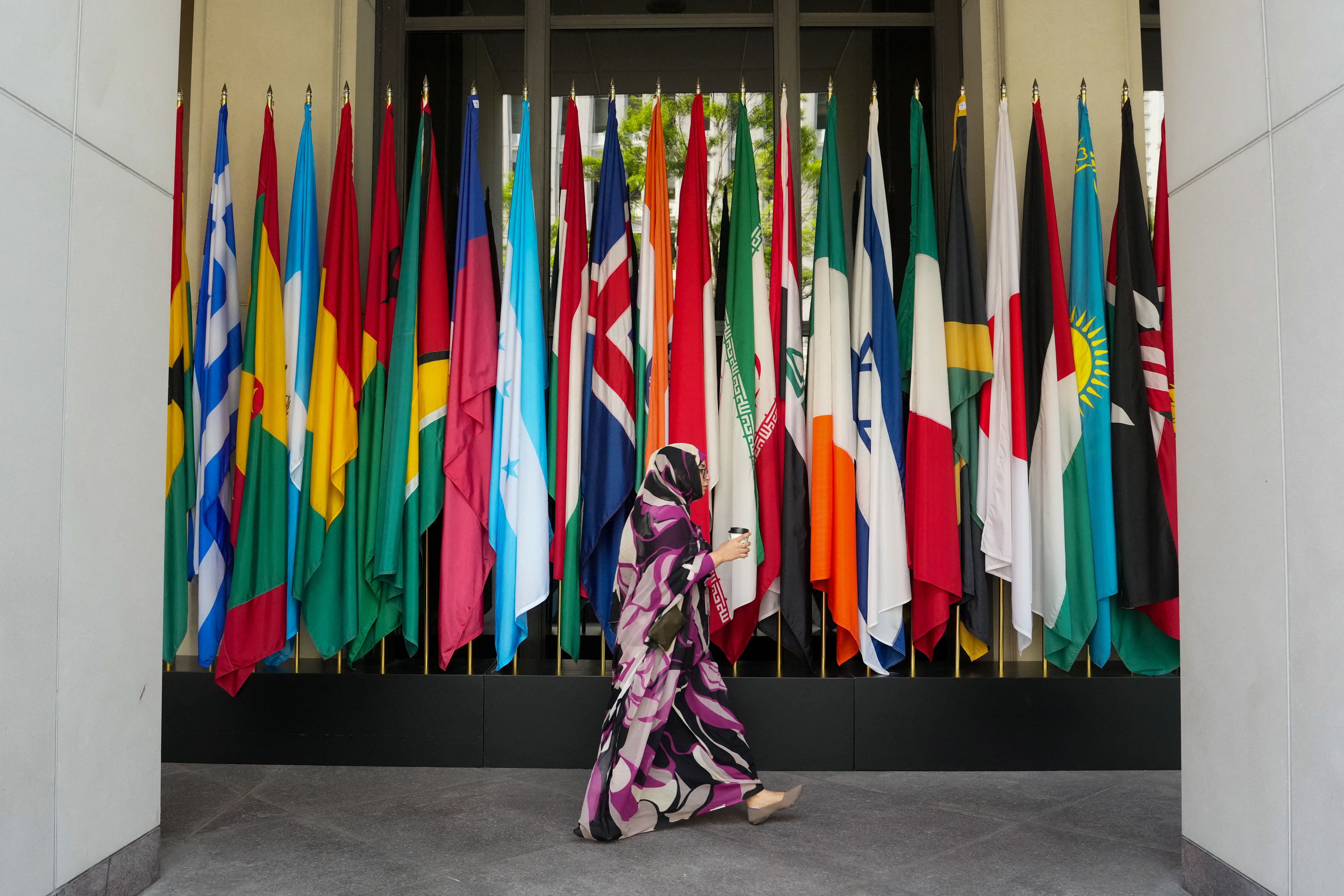 A woman walks by a long row of flags at the IMF building during the 2026 annual IMF/World Bank Spring Meetings in Washington, D.C., U.S., April 16, 2026. 