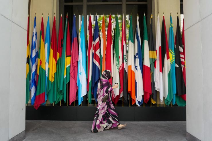 A woman walks by a long row of flags at the IMF building during the 2026 annual IMF/World Bank Spring Meetings in Washington, D.C., U.S., April 16, 2026.