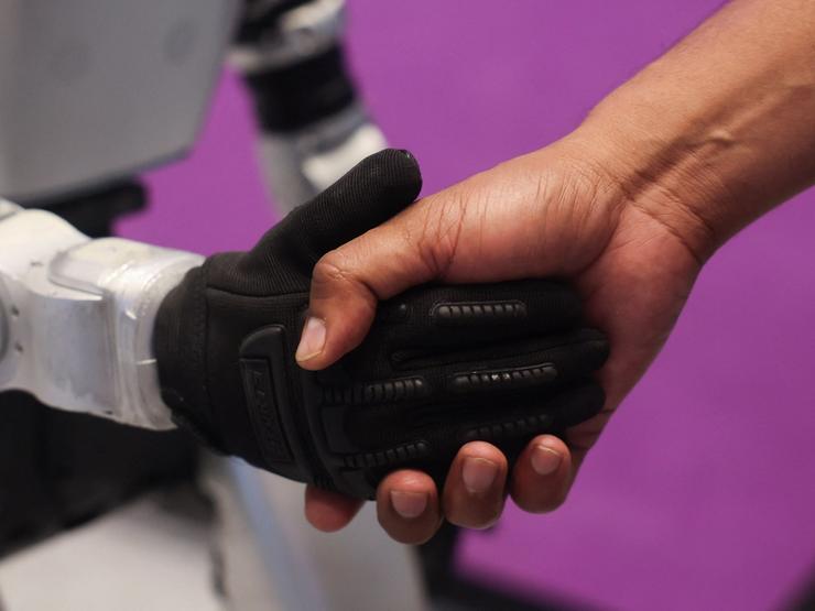 A man shakes the hand of a Chinese G1 humanoid robot.