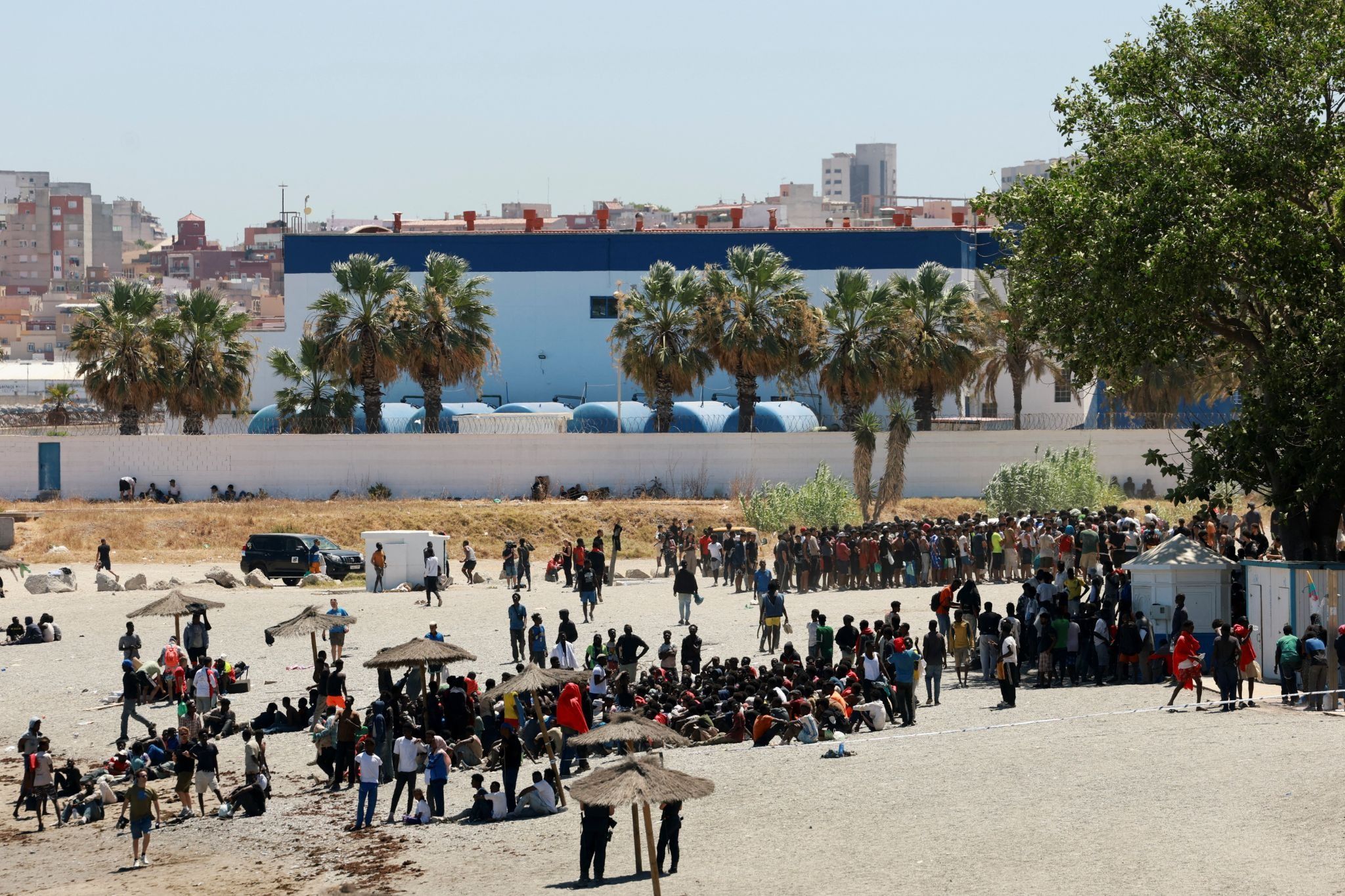 Migrants wait on the beach guarded by police, in Ceuta, Spain.