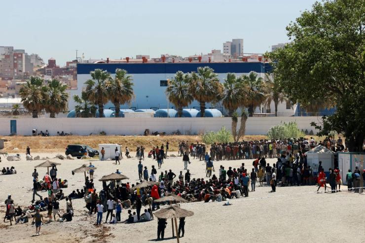 Migrants wait on the beach guarded by police, in Ceuta, Spain.