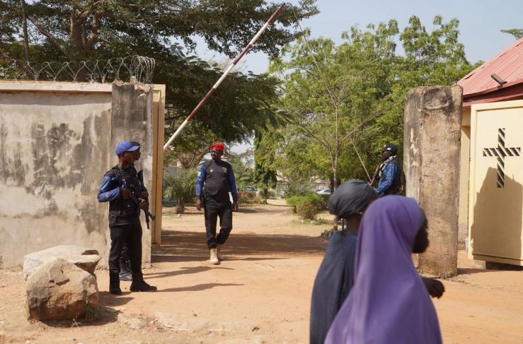 Members of Nigeria’s Civilian Joint Task Force stand guard as people pass in front of ECWA Good News Church in Minna, Niger State, Nigeria, on Nov. 30, 2025.