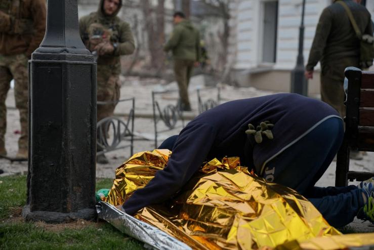 A person in Sumy hugs a body covered by a foil blanket