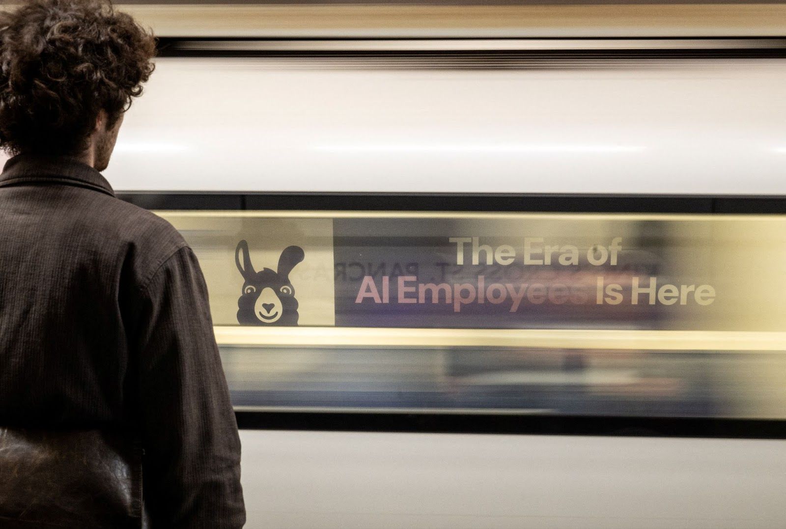 A London underground train passes a billboard for an Artificial Intelligence company advertising AI employees in London.