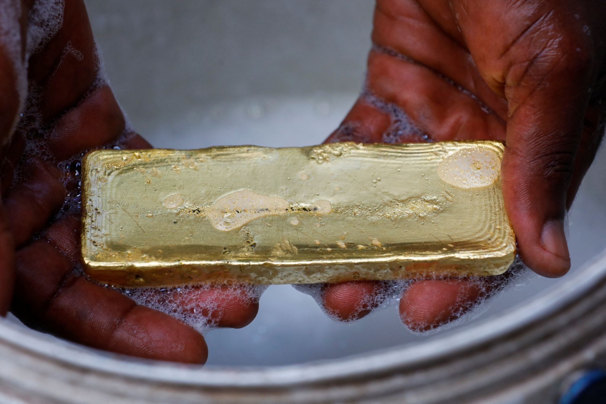 A worker washes off excess impurities during a gold smelting process at a facility in Accra.