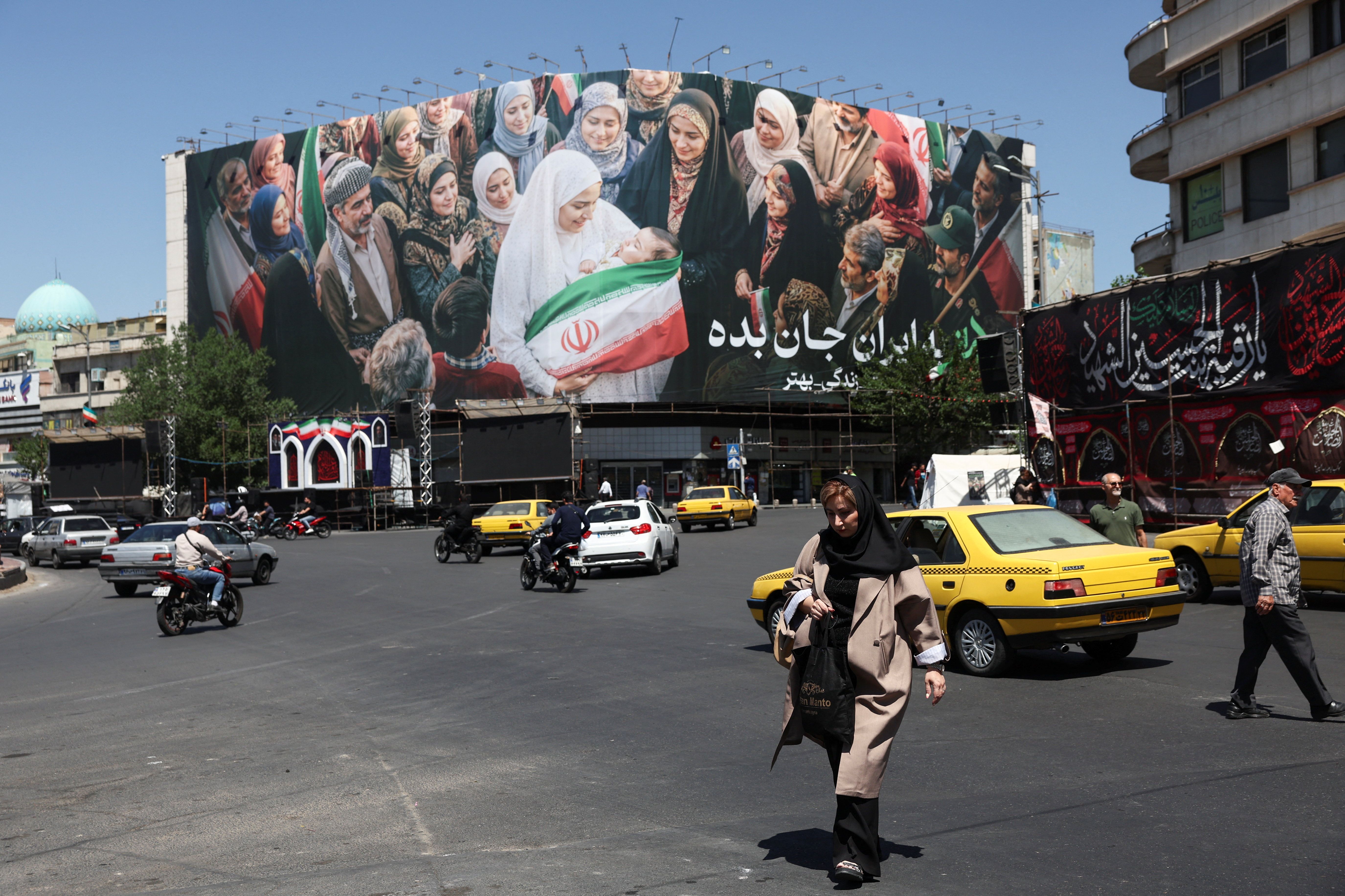 People walk past a billboard with a picture of Iranian people, in Tehran