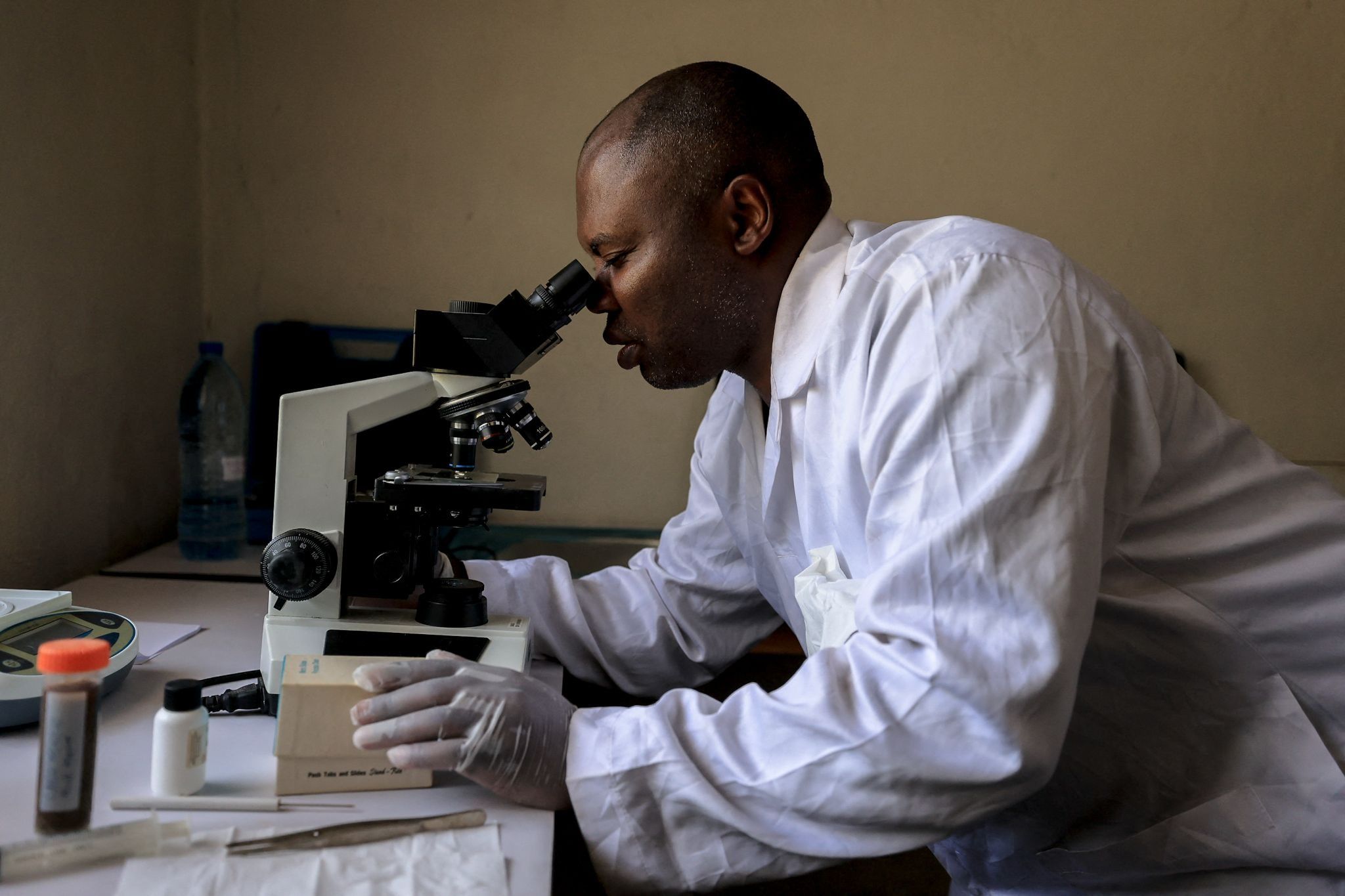 A scientist in Cameroon looks through a microscope.