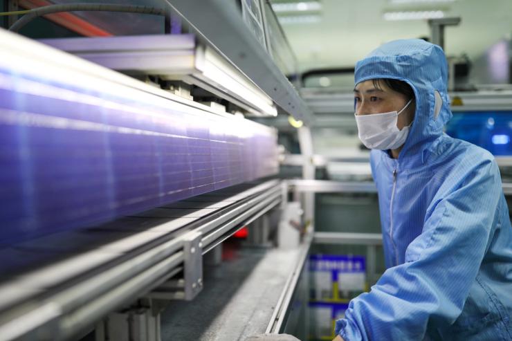 Employee works at a solar panel production line.