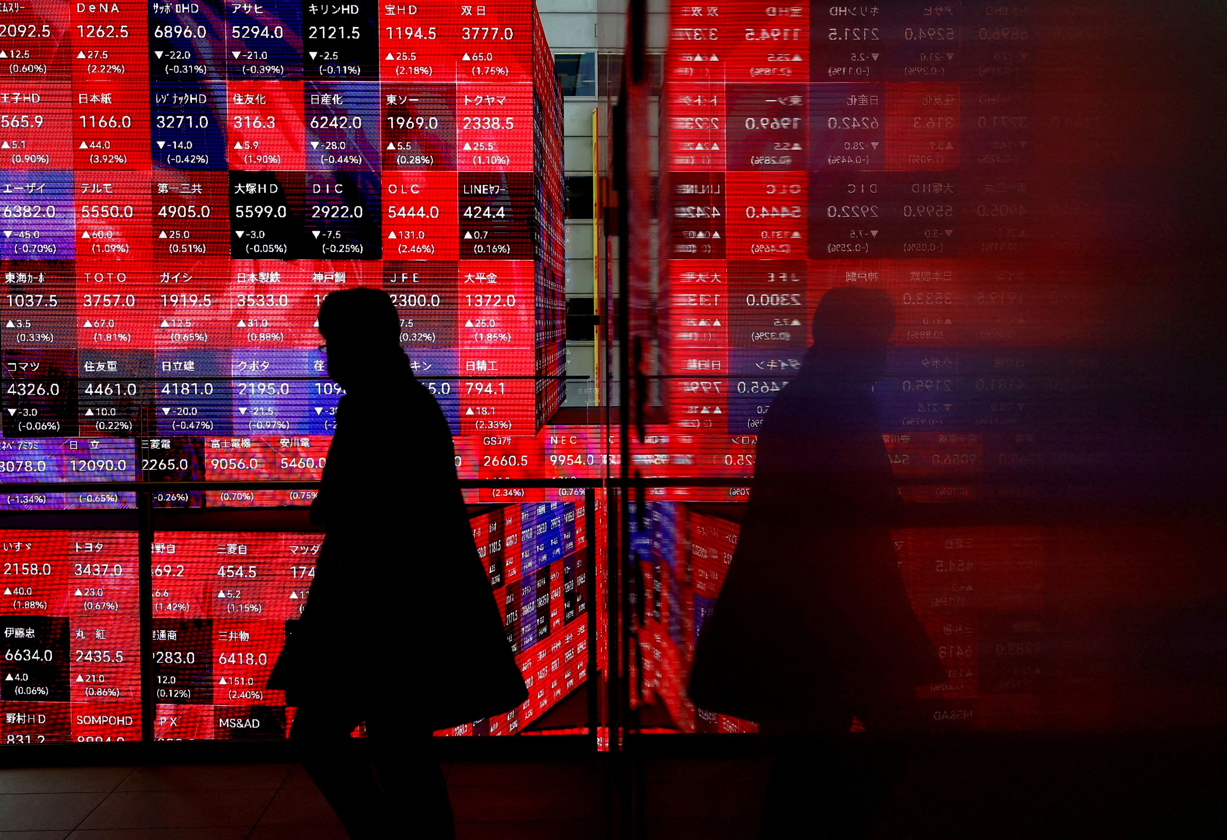 A visitor walks past Japan’s Nikkei stock prices quotation board inside a building in Tokyo.