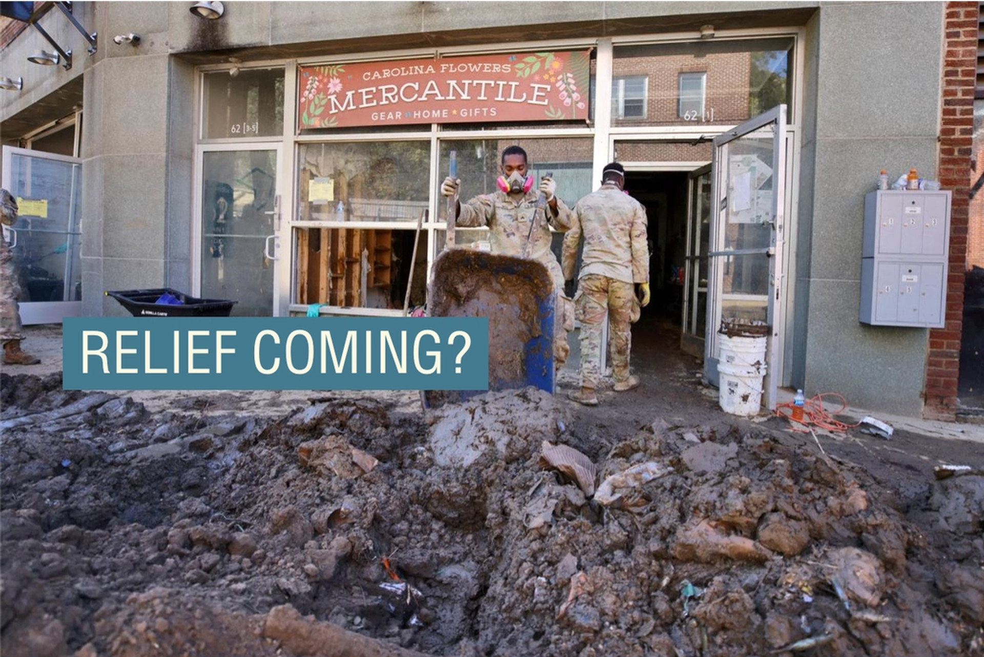 Workers clear out rubble from a destroyed shop front