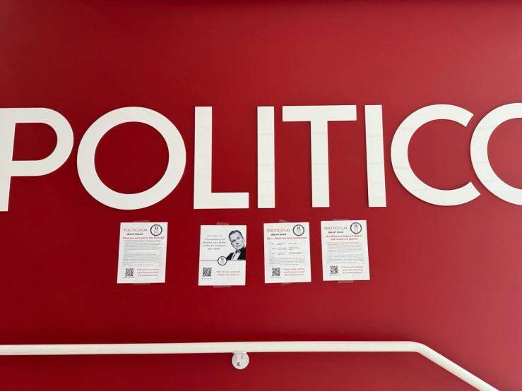 Printouts of AI-generated text taped to a wall in Politico’s office