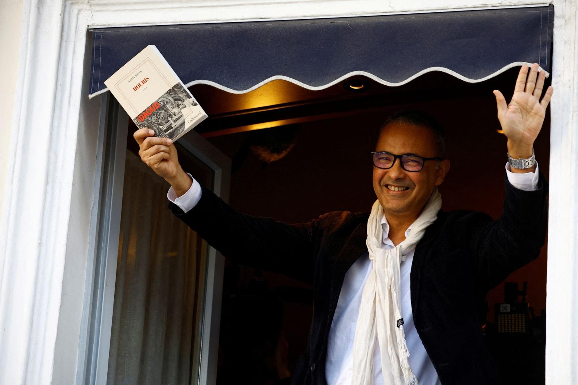 Kamel Daoud waves from a window of the Drouant restaurant after he received the French literary prize Prix Goncourt.