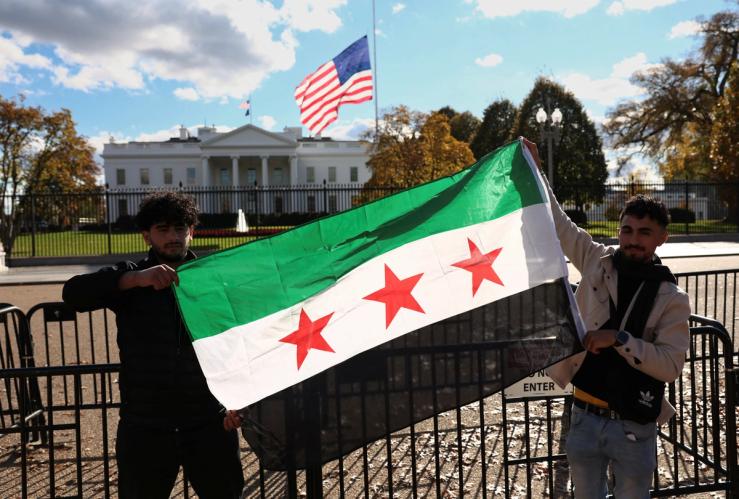 Two demonstrators hold a Syrian flag outside the White House