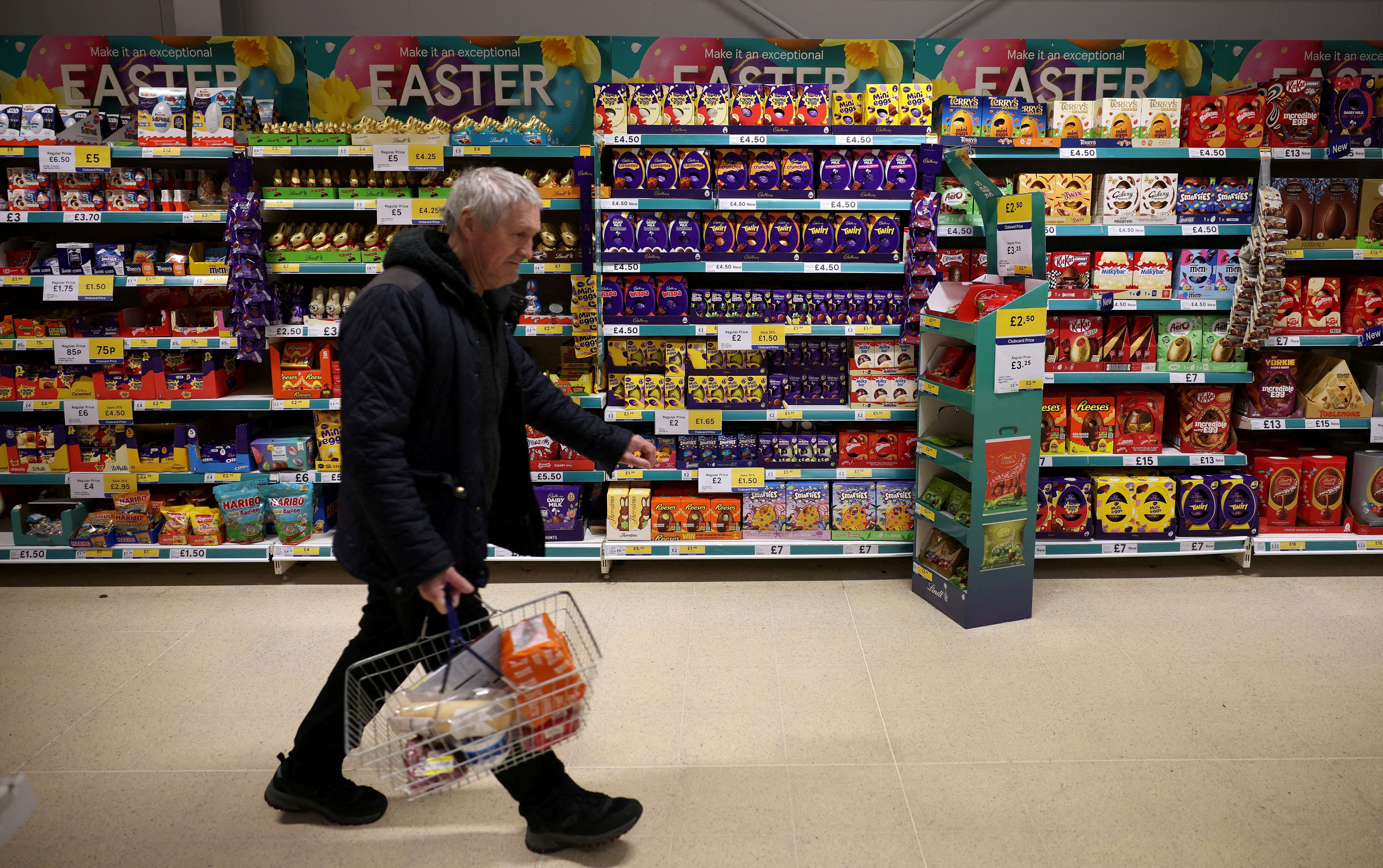 A shopper walks past shelves displaying easter eggs and chocolates inside a Tesco supermarket in Manchester.