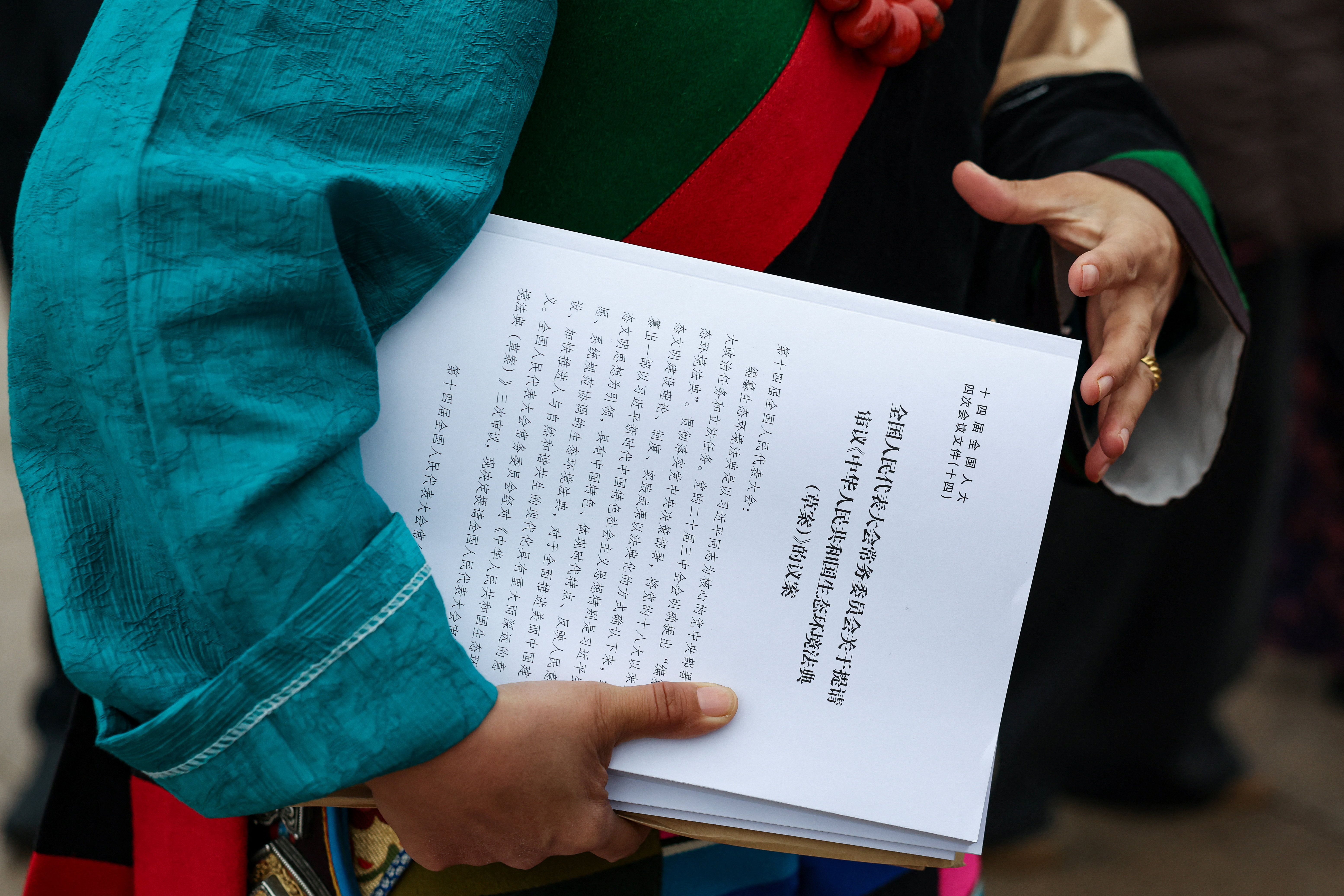 A delegate in an ethnic minority costume from the delegation of the Tibet Autonomous Region leaves holding documents