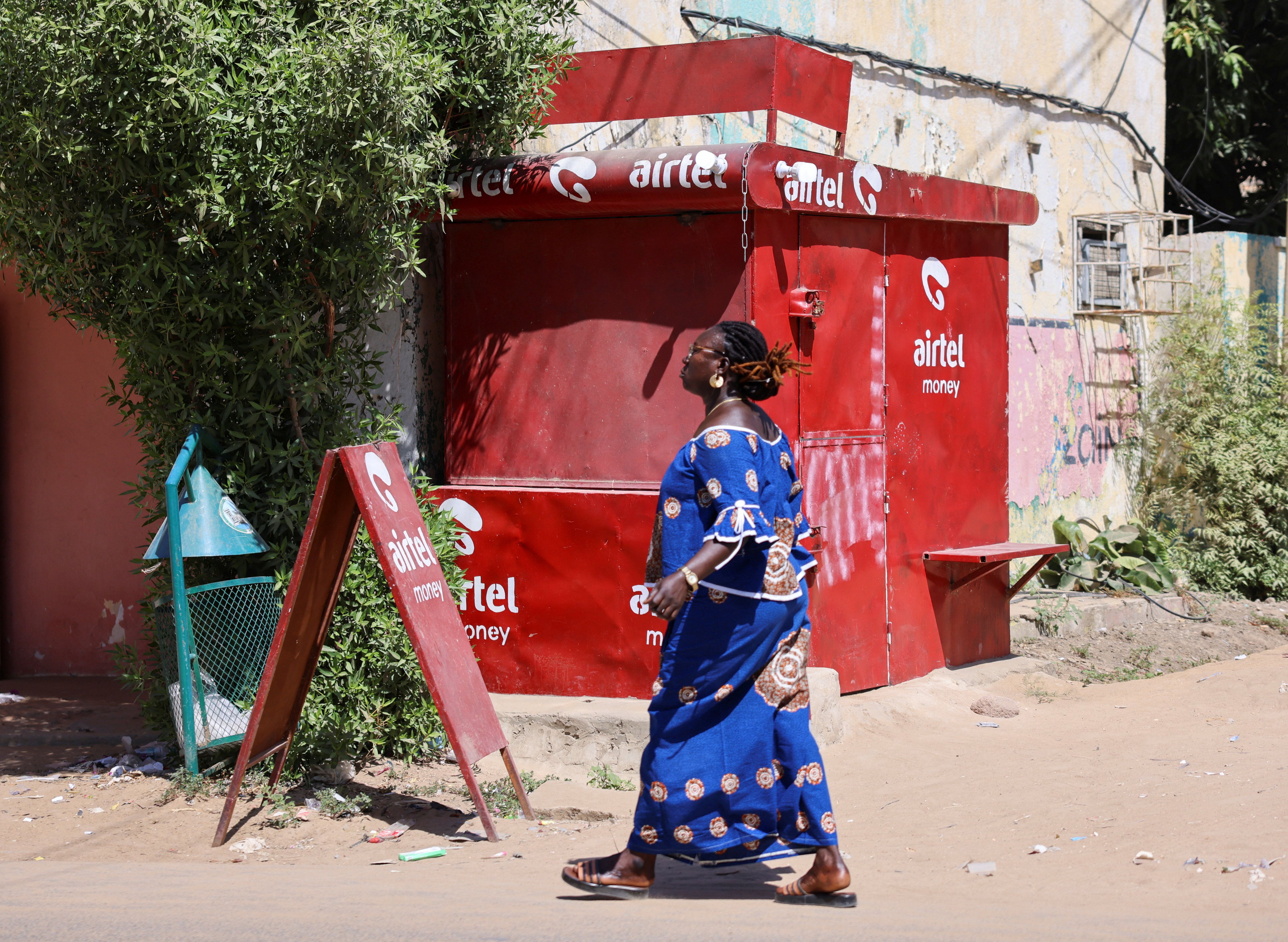 A Chadian woman walks past a closed kiosk of Airtel Africa.