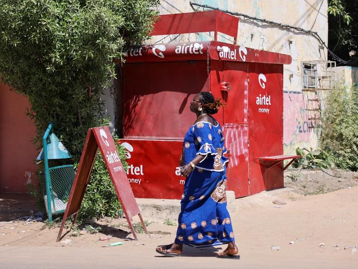 A Chadian woman walks past a closed kiosk of Airtel Africa.