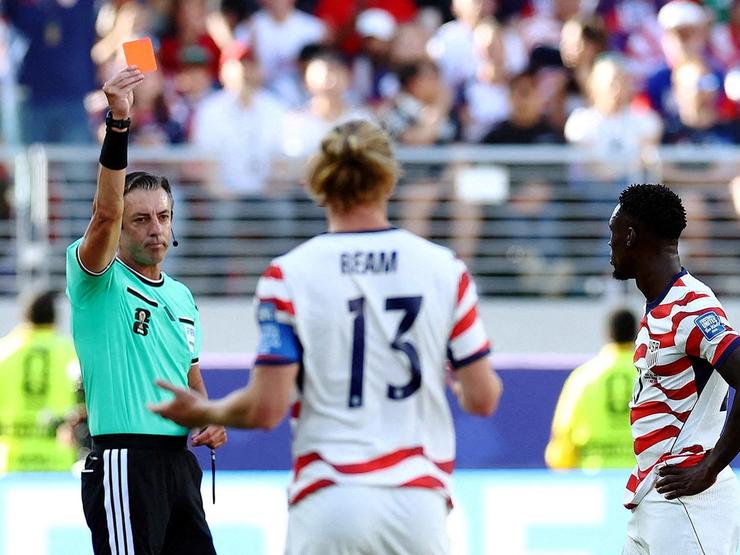 A referee holds up a red card to US striker Folarin Balogun
