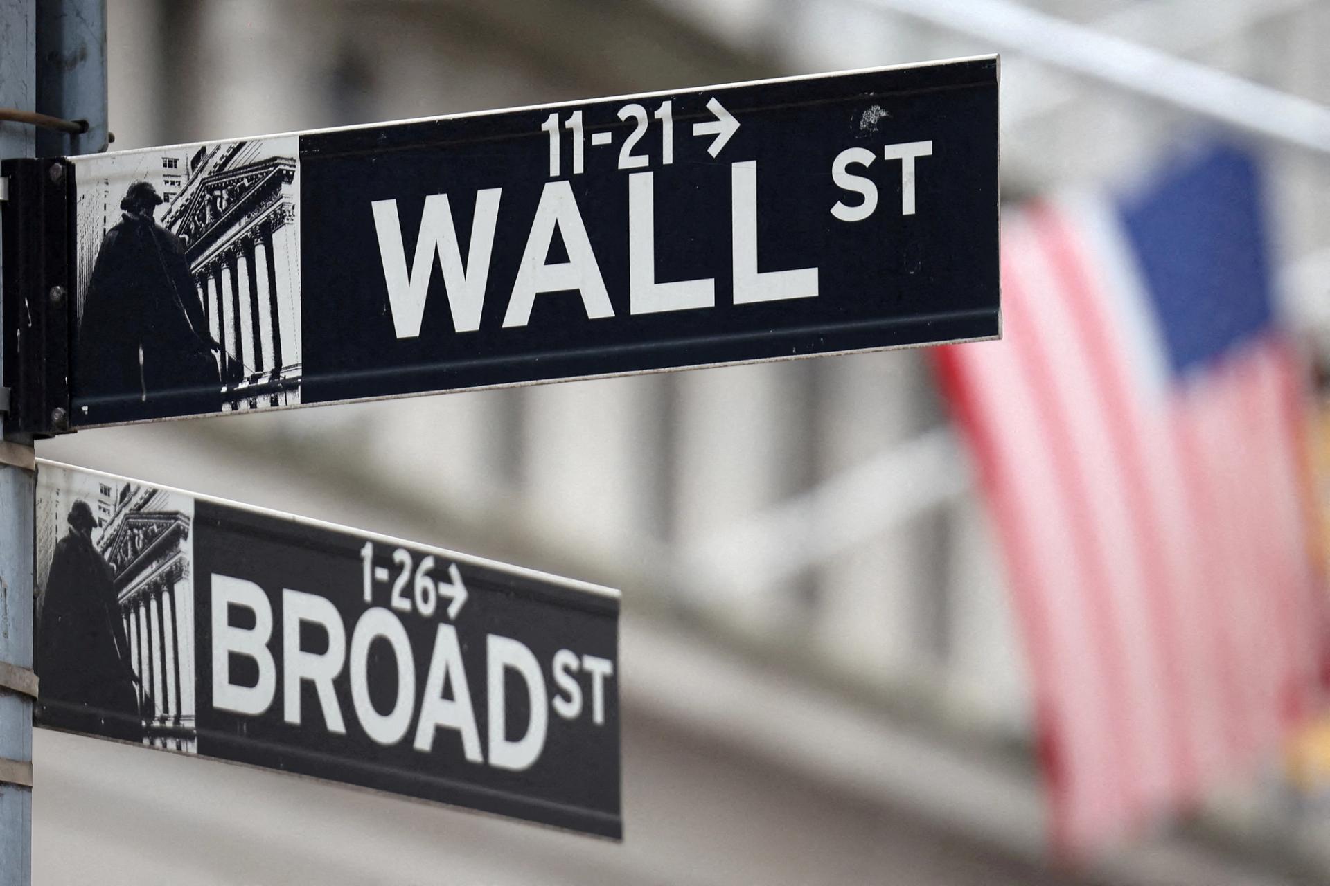 A Wall Street sign hangs in front of a US flag outside the New York Stock Exchange