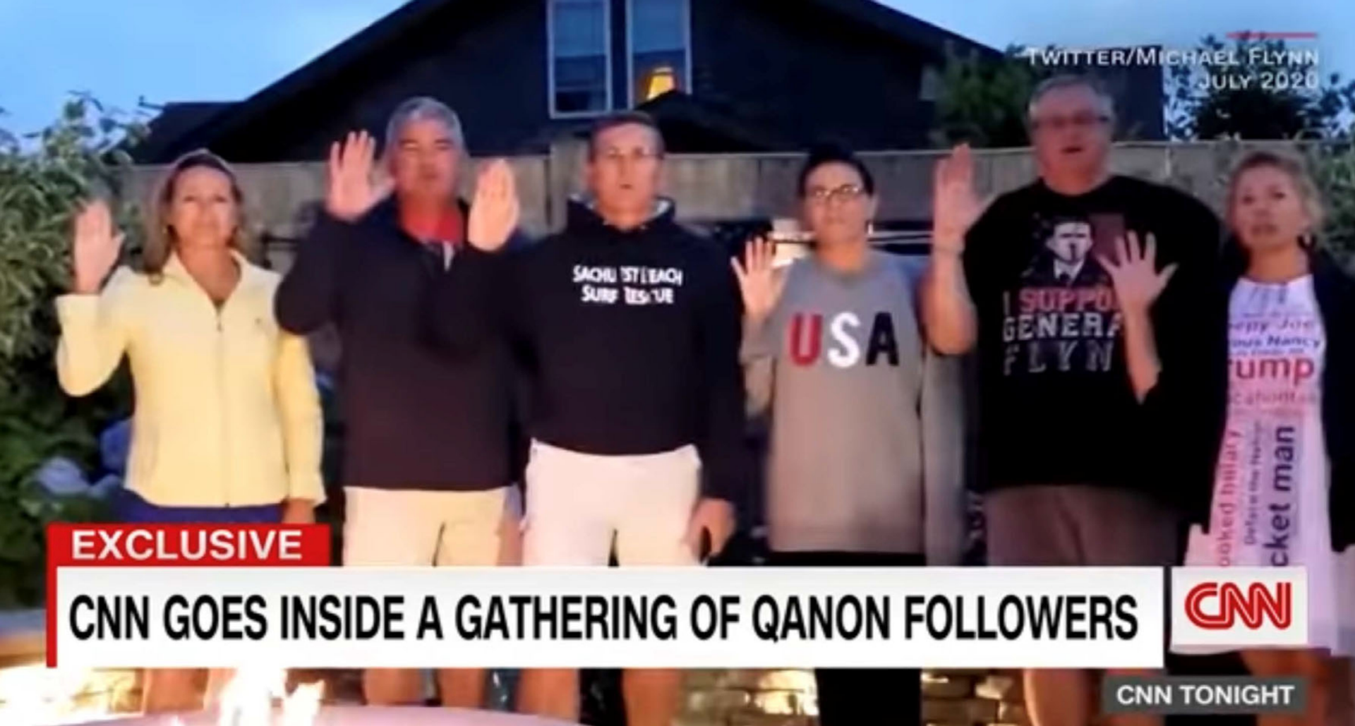 A screenshot from the CNN report of the Flynn family with their hands raised as Michael Flynn says "Where We Go One, We Go All"