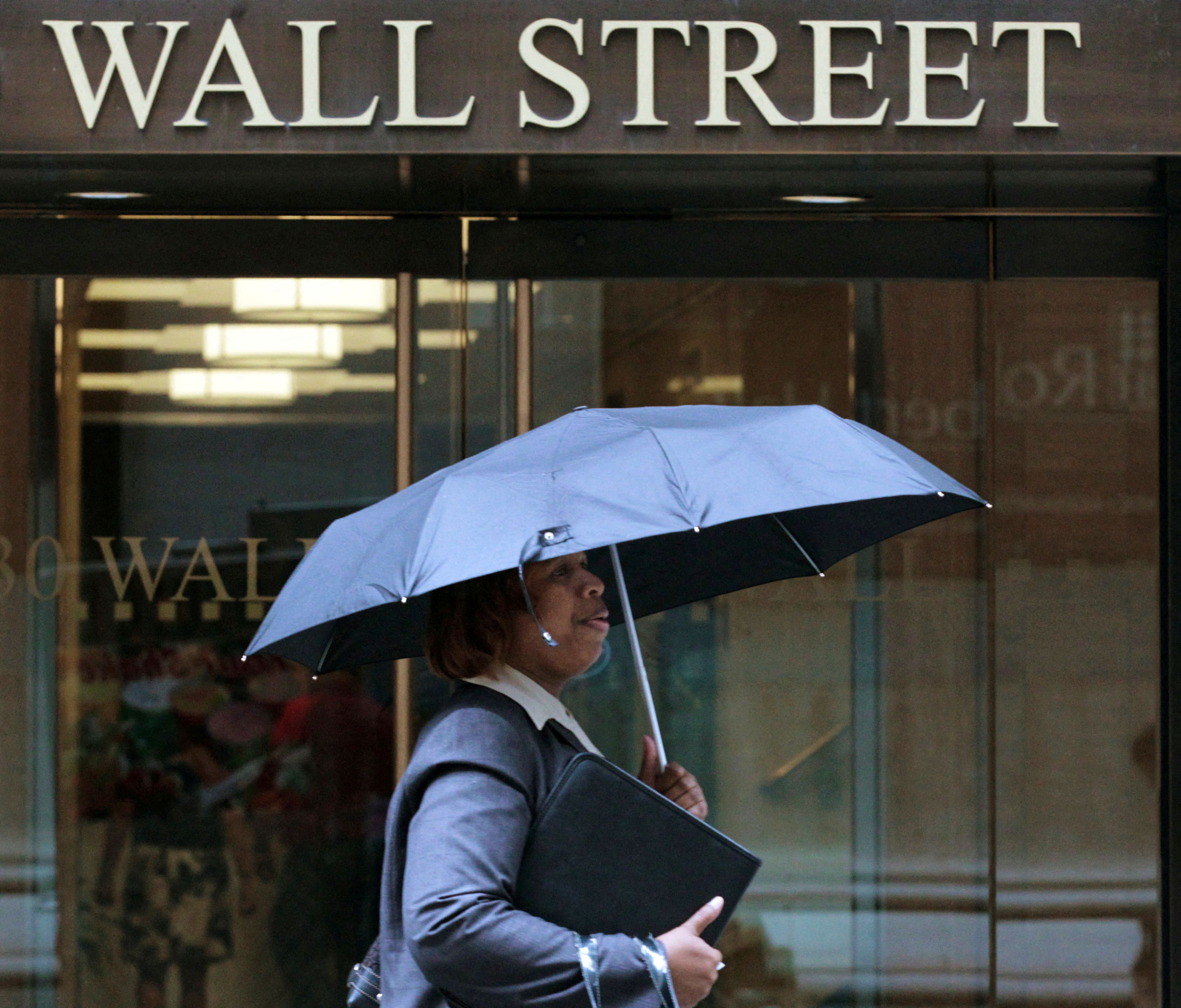 A woman walks through the rain on Wall Street in New York, August 16, 2011.