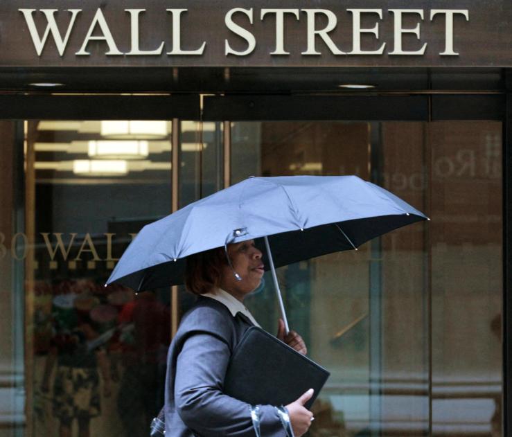 A woman walks through the rain on Wall Street in New York, August 16, 2011.