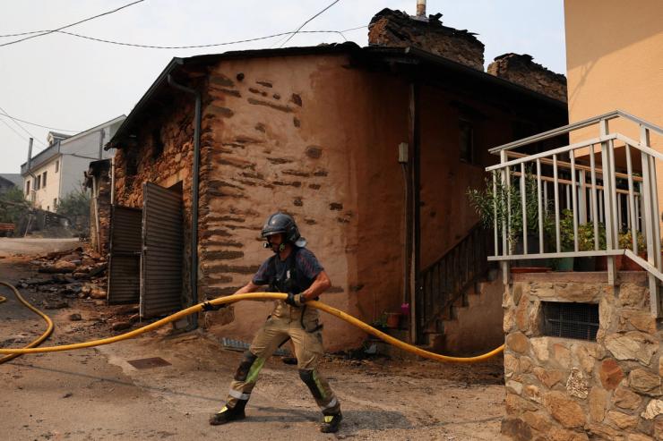 A firefighter works next to a burned house after a wildfire in Spain.
