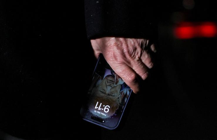 Donald Trump holding a phone with himself on the lock screen