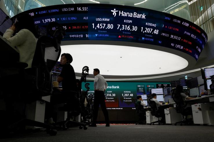 Currency dealers work as an electronic board displays the Korea Composite Stock Price Index