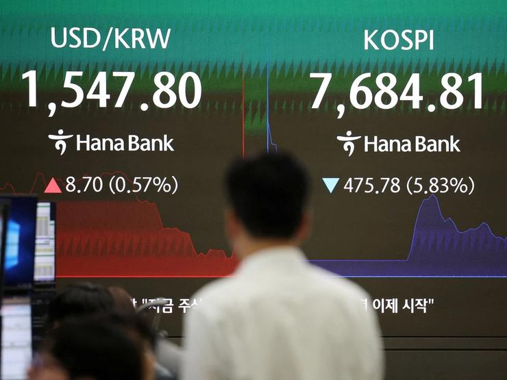 A currency dealer looks at an electronic board displayed the exchange rate between the US dollar and the South Korean won and the KOSPI in a bank in Seoul.