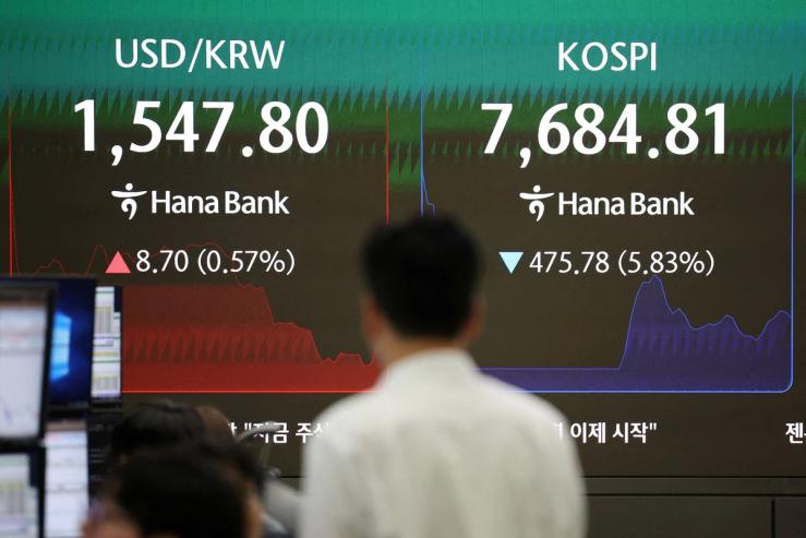 A currency dealer looks at an electronic board displayed the exchange rate between the US dollar and the South Korean won and the KOSPI in a bank in Seoul.
