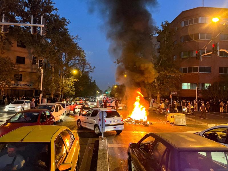 A police motorcycle burns during a protest over the death of Mahsa Amini, a woman who died after being arrested by the Islamic republic’s “morality police”, in Tehran, Iran