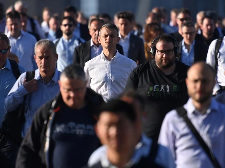 Workers walk towards the City of London financial district as they cross London Bridge during the morning rush hour in London, Britain