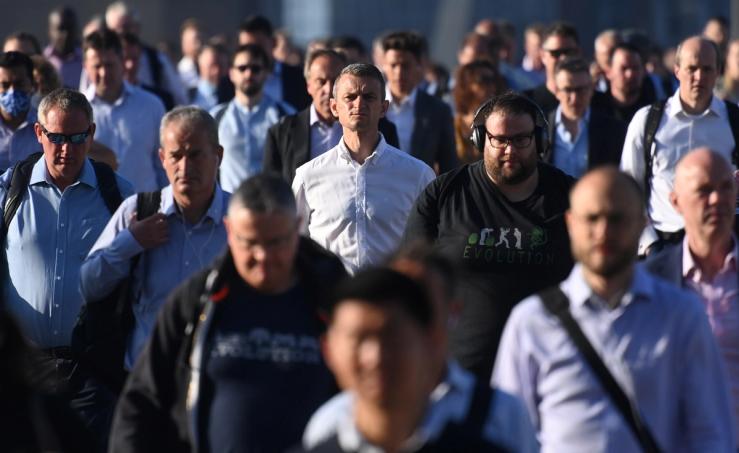 Workers walk towards the City of London financial district as they cross London Bridge during the morning rush hour in London, Britain