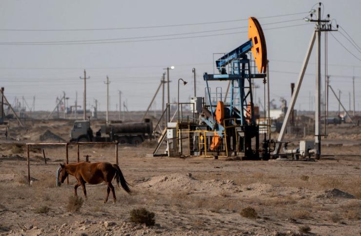 A horse grazes near an oil drilling rig of OzenMunayGaz company in Zhanaozen in the Mangystau region, Kazakhstan, November 14, 2023.