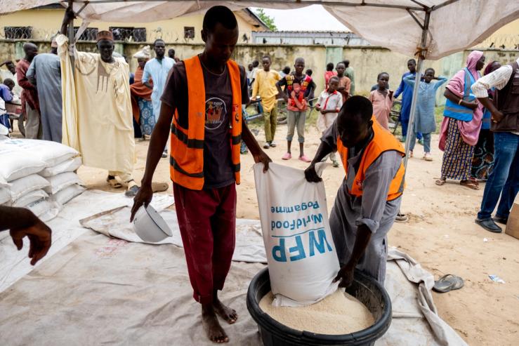 Two men empty a bag of rice into a bowl at a WFP distribution centre in Mafa, Borno State, Nigeria.