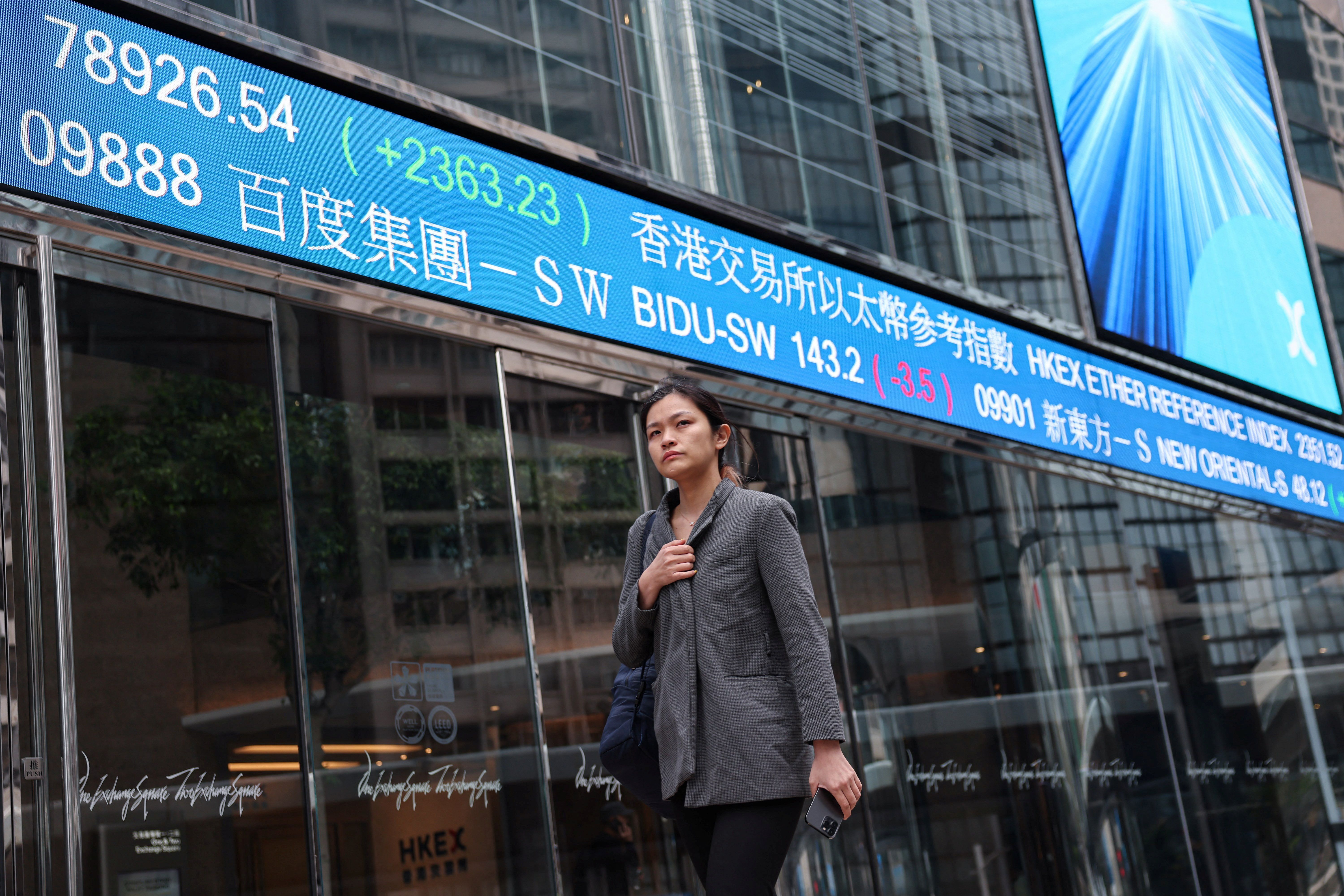 A screen displays the Hang Seng stock index at Central district, in Hong Kong, China.