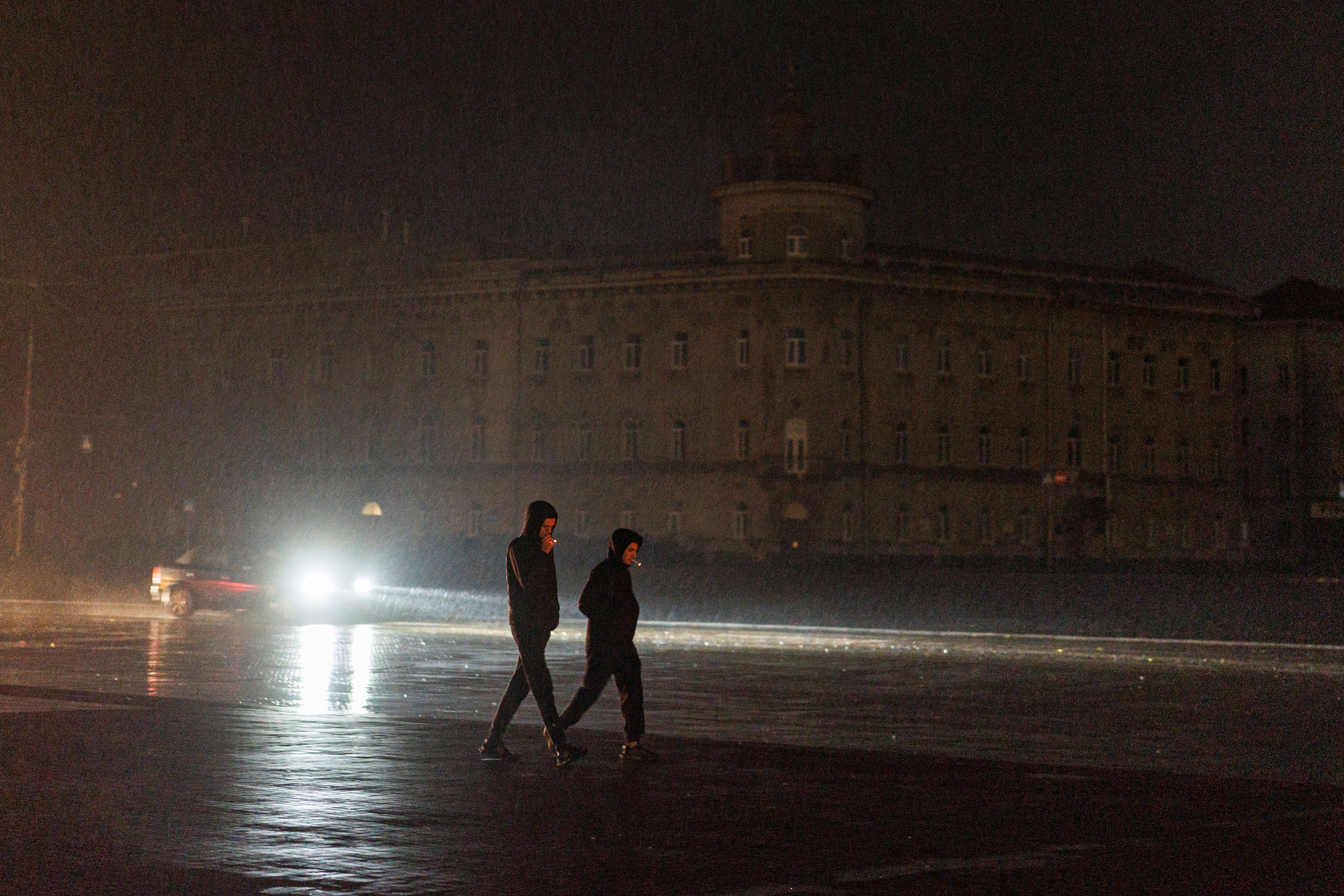 Young men walk in the dark across a main square during a power outage in Chernihiv.