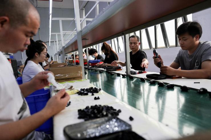 Employees work at an assembly line producing car smartphone holders.