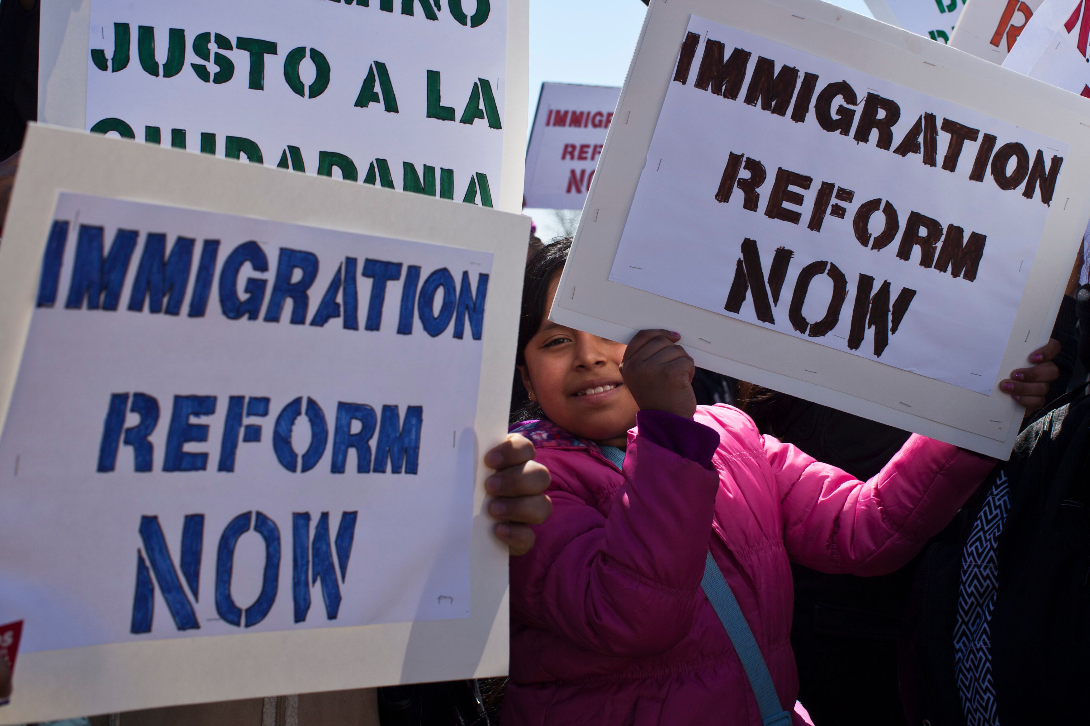 A girl holds up a banner that says “immigration reform now”