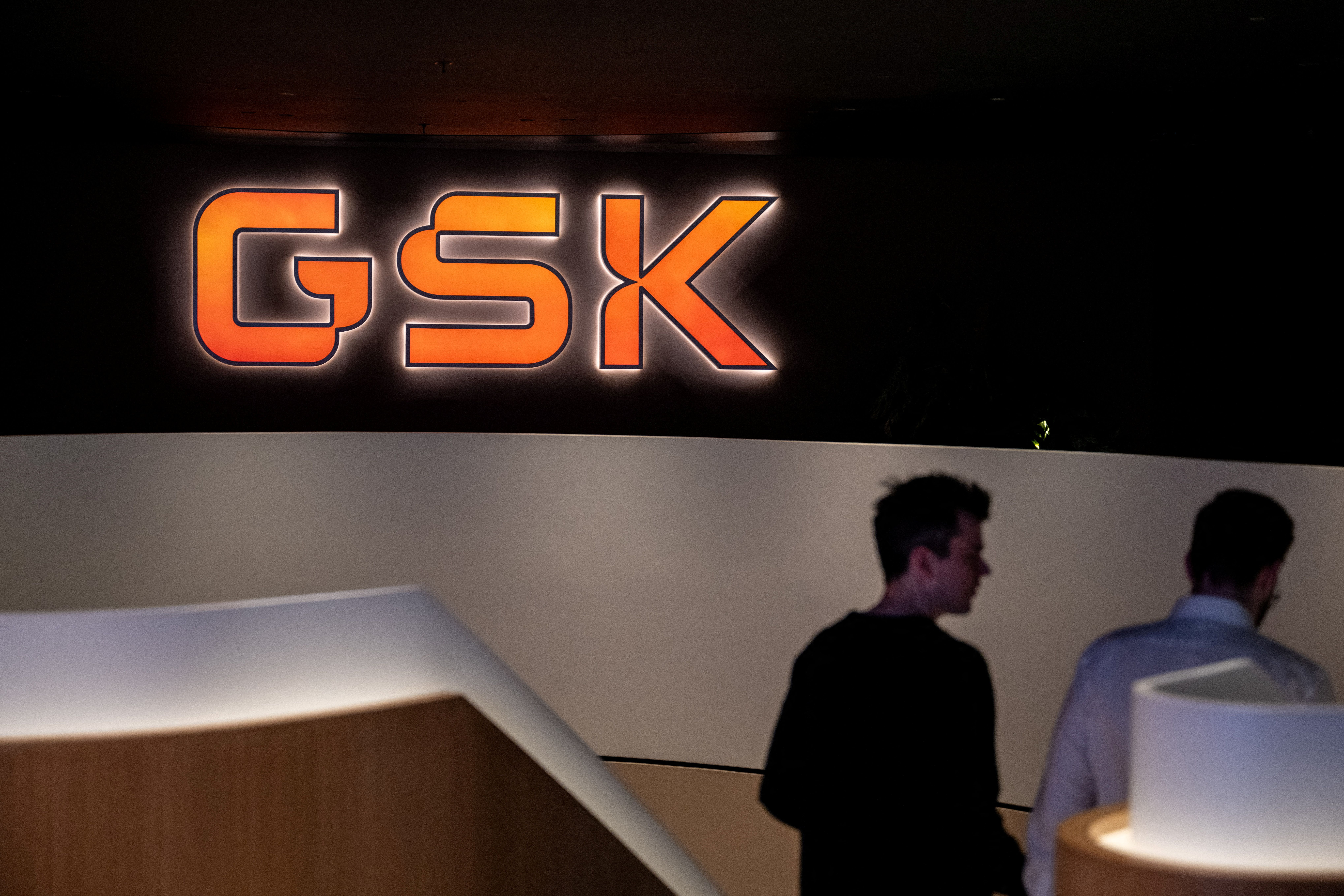 Staff members walk down stairs in the main lobby of GSK offices
