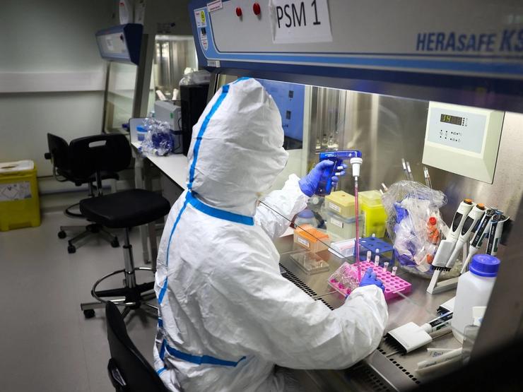 A researcher wearing protective suit works during a press visit at the Institut Pasteur.